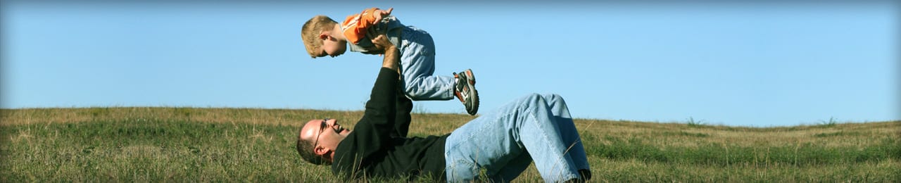 A photo of a father and son playing in the grass