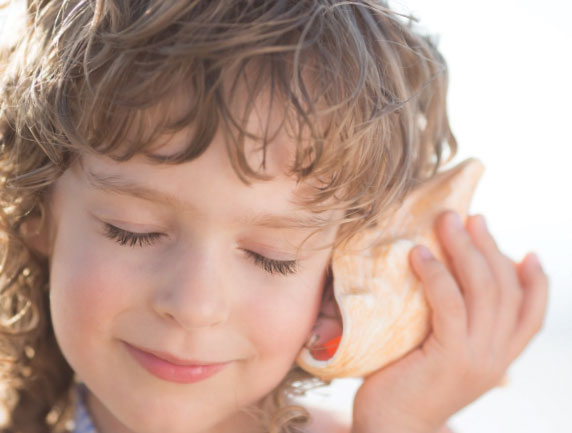 A photo of a young boy listening to a sea shell